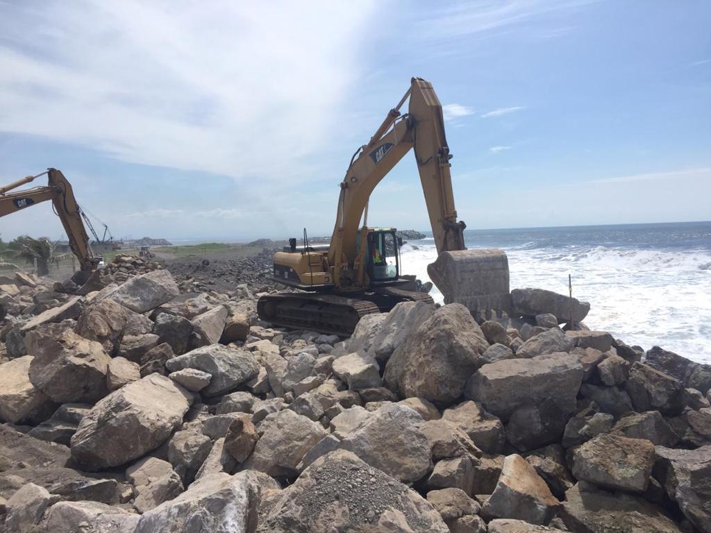 Maquinaria pesada sobre rocas en frente marítimo