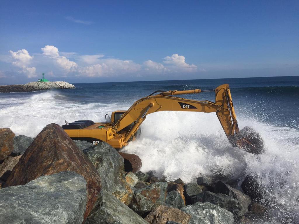 Excavadora operando entre oleaje en protección costera