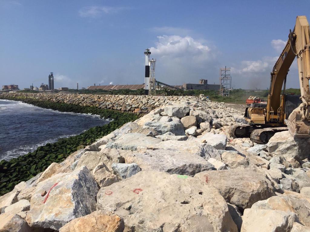 Escollera costera terminada con maquinaria al fondo